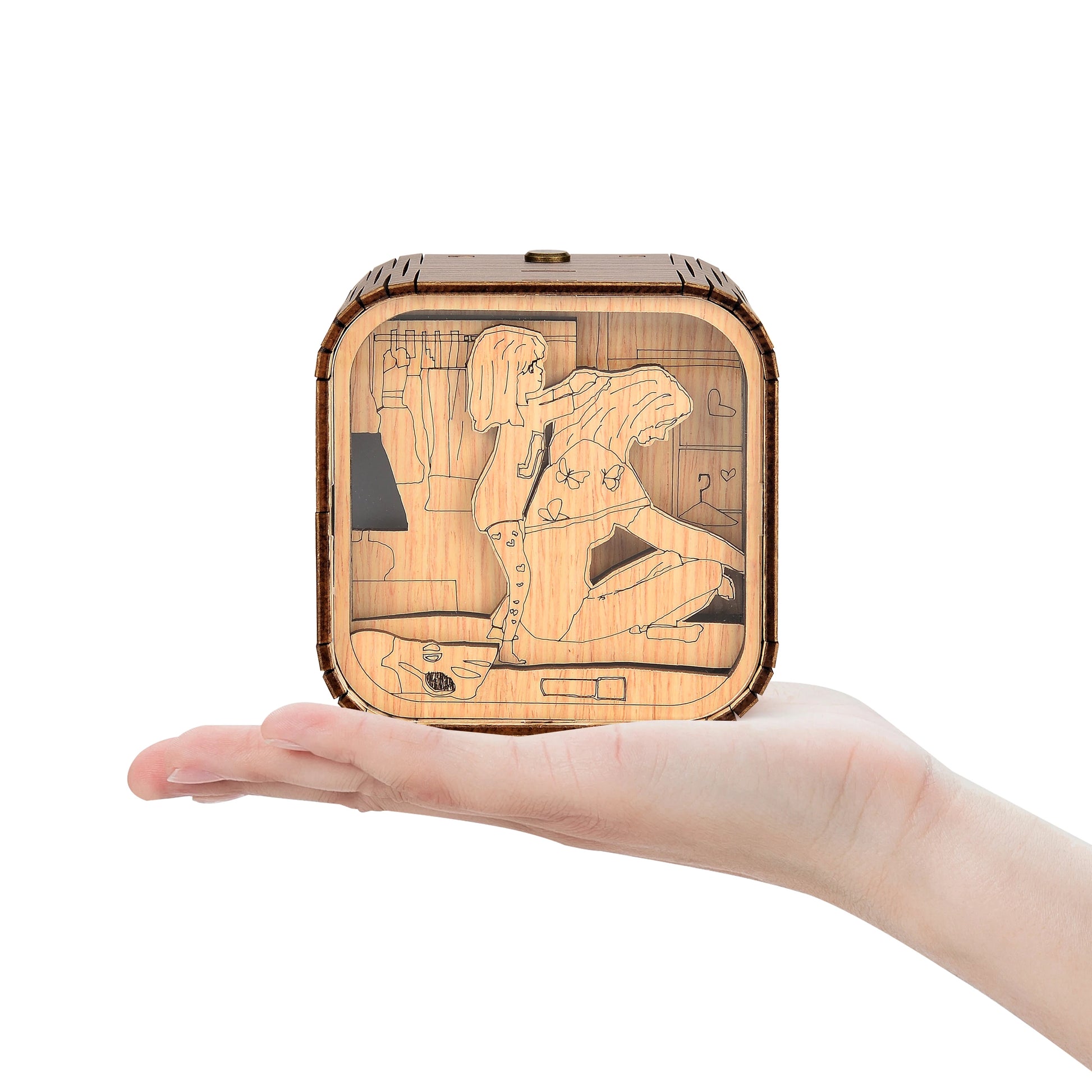 Boîte à musique veilleuse en bois, tenue dans une main, avec une illustration gravée d'une petite fille