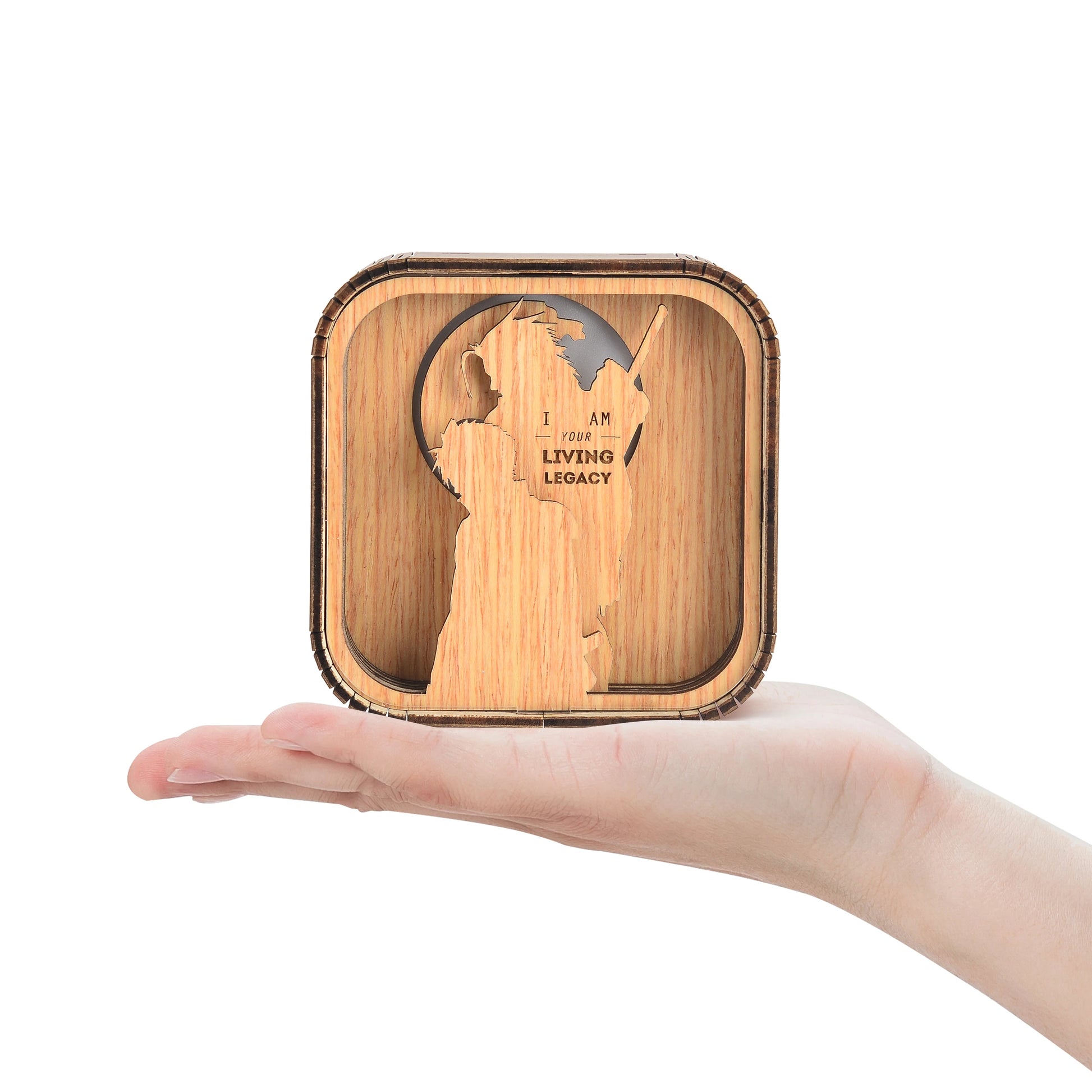Boîte à musique veilleuse en bois clair, en forme de cube, avec une découpe silhouette d'homme. Tenue sur une paume.