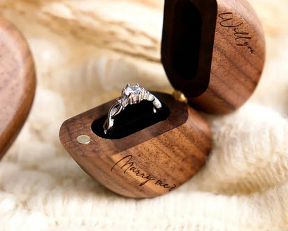Boîte à bague cœur en bois de noyer ouverte, avec une bague en argent ornée d'un diamant et gravée