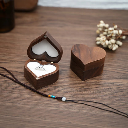 Deux boîtes à bijoux en bois de noyer en forme de cœur, une ouverte avec une bague, l'autre fermée.