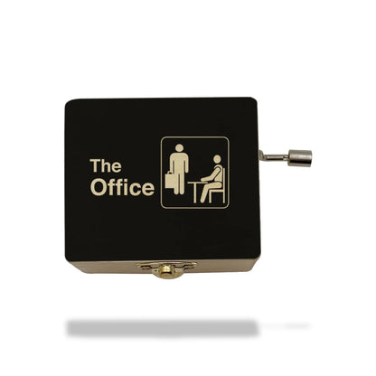 Boîte à musique noire en bois avec couvercle marqué "The Office" et pictogrammes d'employés, manivelle latérale.
