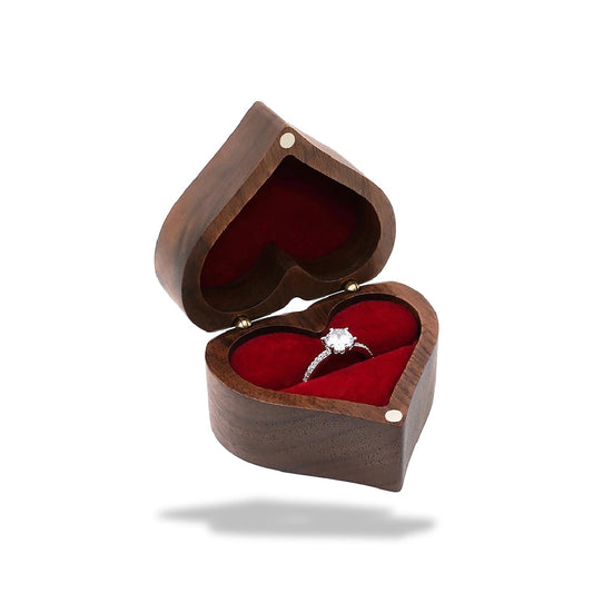Boîte à bijoux en forme de cœur en bois de noyer. Le couvercle entrouvert révèle un intérieur en velours rouge et une bague.