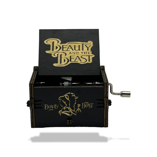 Boîte à musique en bois noir, ouverte, avec motifs dorés "Beauty and the Beast" et deux silhouettes.