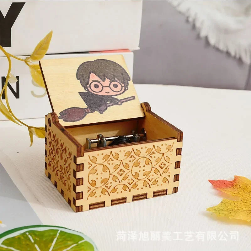 Boîte à musique rectangulaire en bois clair, couvercle ouvert avec un dessin de Harry Potter sur balai. Motifs gravés sur les