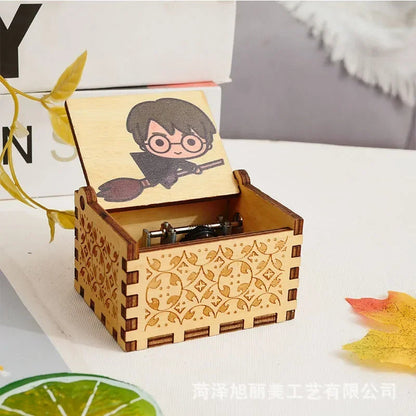 Boîte à musique rectangulaire en bois clair, couvercle ouvert avec un dessin de Harry Potter sur balai. Motifs gravés sur les