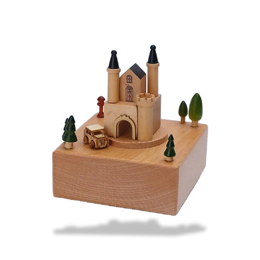 Boîte à musique en hêtre représentant un château avec des tourelles noires, une voiture et des arbres miniatures.