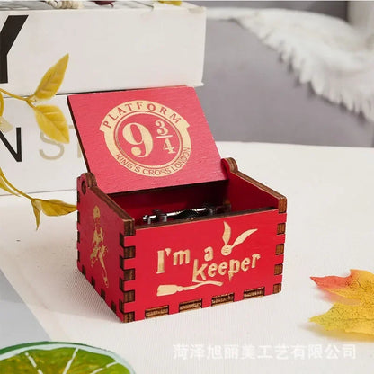 Boîte à musique rouge en bois, couvercle ouvert, avec le logo Platform 9 3/4 et l'inscription 'I'm a Keeper'.