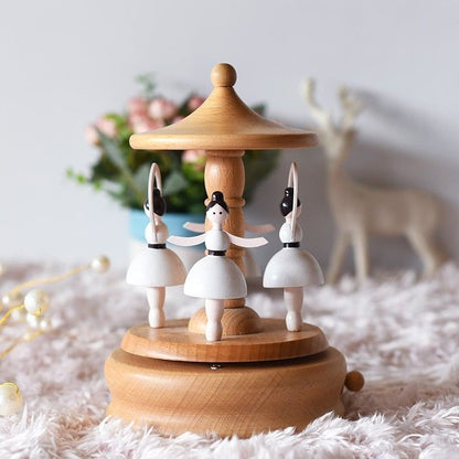 Boîte à musique en hêtre clair avec trois ballerines blanches et noires rotatives sur un socle.