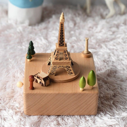 Boîte à musique en hêtre, représentant une Tour Eiffel et des éléments urbains et naturels en bois, sur un socle rectangulair