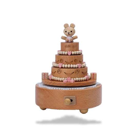 Boîte à musique en bois clair en forme de gâteau d'anniversaire à cinq niveaux, décorée de cœurs et perles roses, surmontée d