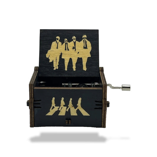 Boîte à musique en bois noir, ouverte, avec motifs dorés des Beatles sur le couvercle et l'avant. Manivelle visible.
